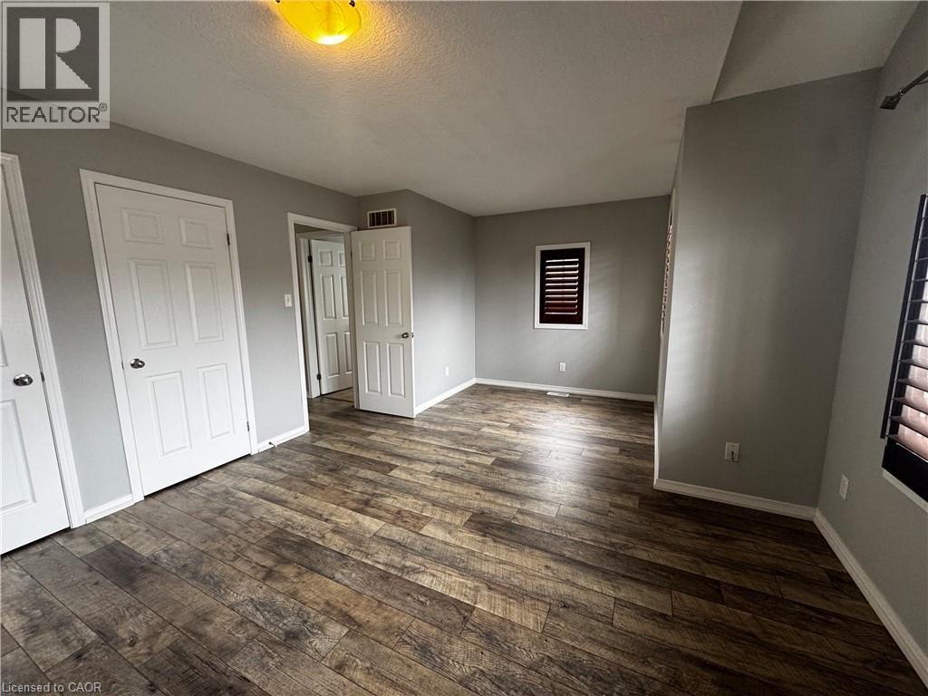 Spacious room featuring wood-finish flooring, light gray wall paint, and white trim - 13 Sorrento Street, Kitchener, ON - Indoor Photo Showing Other Room