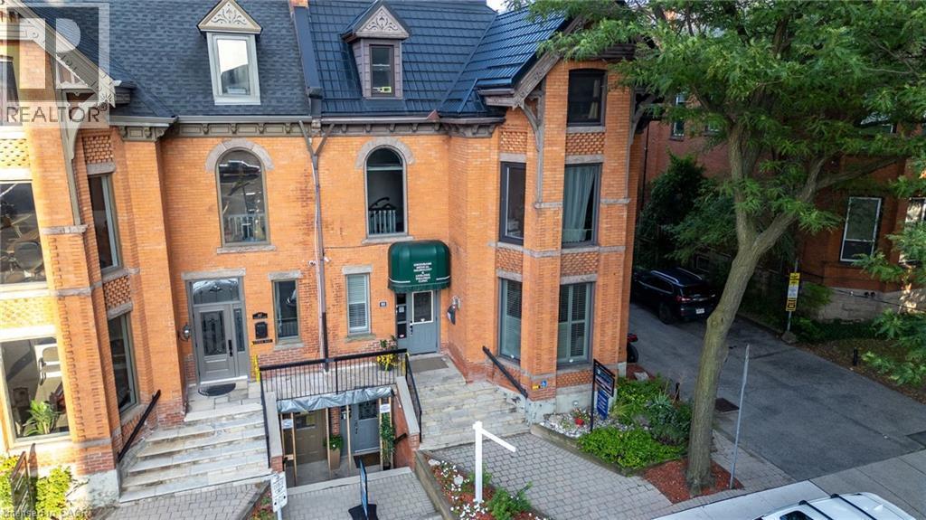 Historic brick facade with intricate architectural details, multiple arched windows, and a dark tile roof - 189 Hughson Street, Hamilton, ON
