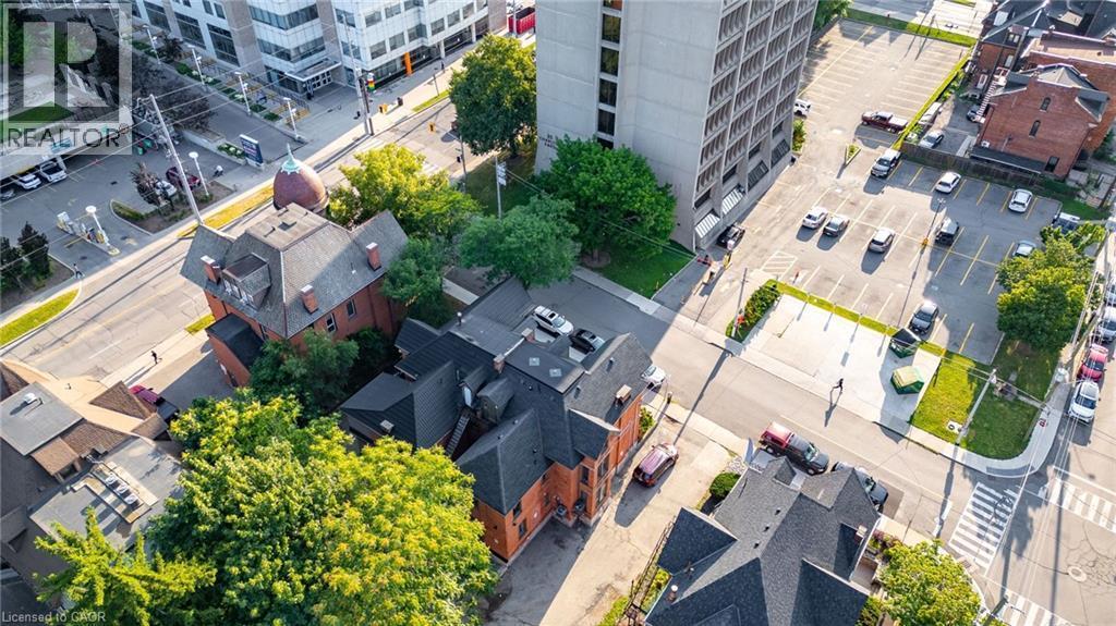 Aerial perspective showcasing a multi-story building with a distinctive red brick exterior and a complex dark-colored roofline - 189 Hughson Street, Hamilton, ON