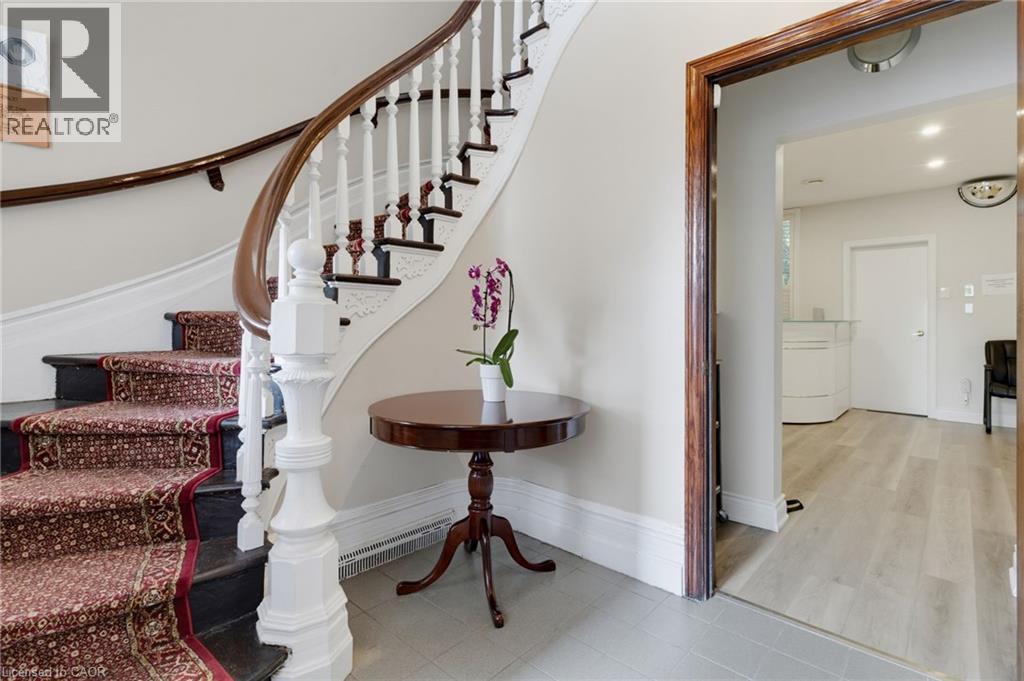 Grand staircase featuring a dark wood handrail, white balusters, and a decorative newel post - 189 Hughson Street, Hamilton, ON