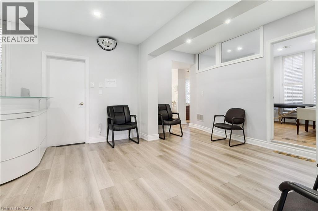 Reception area featuring light wood-finish flooring, recessed lighting, and a modern white reception desk with a glass top - 189 Hughson Street, Hamilton, ON