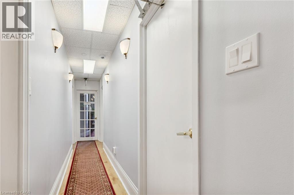 Hallway featuring wall sconces, recessed lighting, and a paneled glass door - 189 Hughson Street, Hamilton, ON