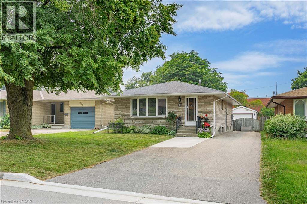 Stone facade bungalow with a single-car driveway, mature front yard tree, and an exterior side entrance - 111 Kimberly Crescent, Kitchener, ON - Outdoor With Facade