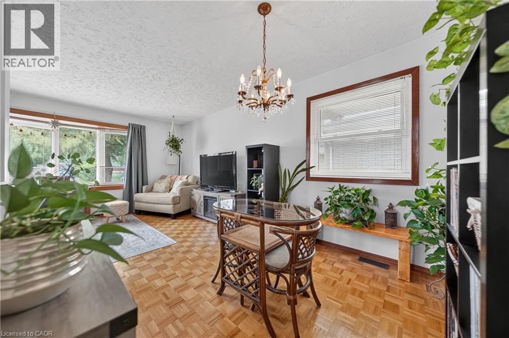 Parquet wood-finish flooring extends throughout this interior space, featuring a crystal chandelier and light grey walls - 111 Kimberly Crescent, Kitchener, ON - Indoor