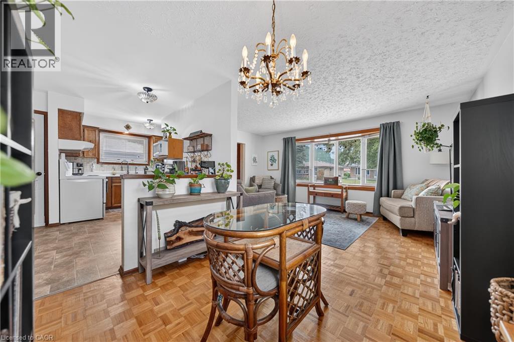 Open-concept living area featuring parquet wood-finish flooring, a decorative chandelier, and a bay window - 111 Kimberly Crescent, Kitchener, ON - Indoor