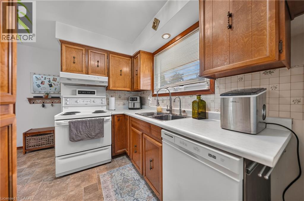 Kitchen featuring wood cabinetry, white countertops, a double basin stainless steel sink with dual faucets, an electric range, and a dishwasher - 111 Kimberly Crescent, Kitchener, ON - Indoor Photo Showing Kitchen With Double Sink