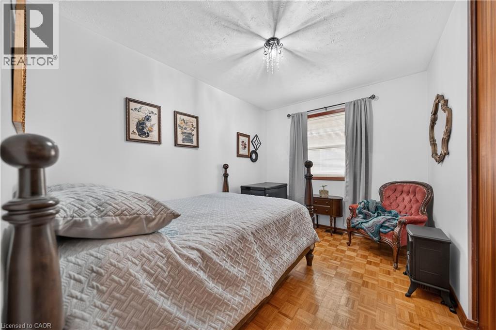 Bright bedroom featuring wood-finish parquet flooring, white walls, and a window with blinds and gray drapes - 111 Kimberly Crescent, Kitchener, ON - Indoor Photo Showing Bedroom