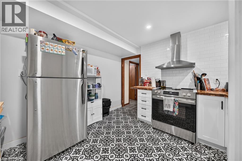 Kitchen featuring patterned flooring, white subway tile backsplash, stainless steel range with overhead vent hood, white cabinetry, and wood-finish countertops - 111 Kimberly Crescent, Kitchener, ON - Indoor Photo Showing Kitchen