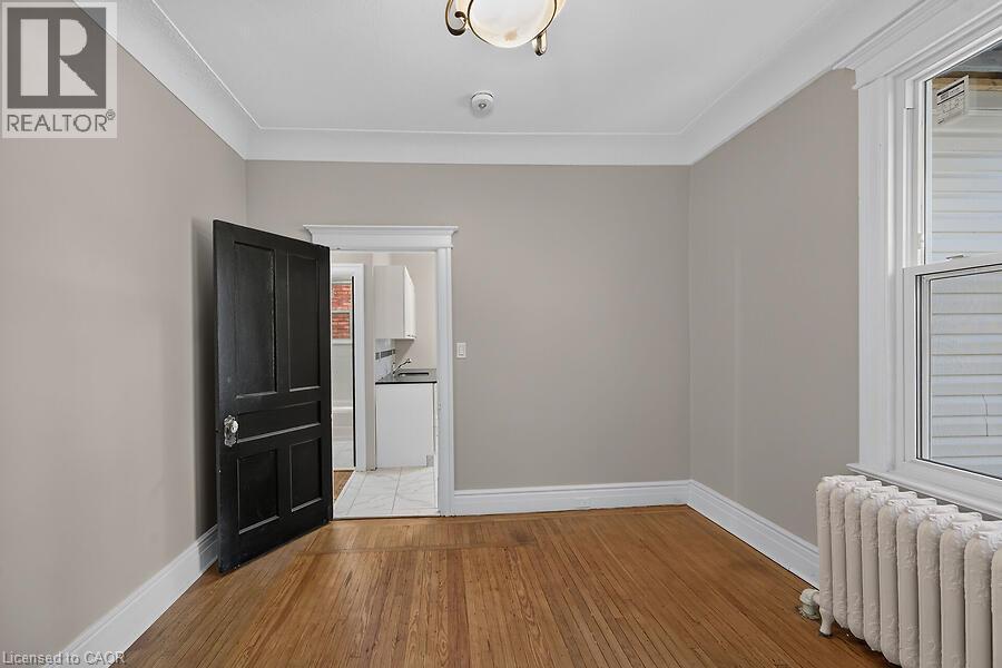 Room featuring wood-finish flooring, neutral wall paint, and white crown molding - 103 Mary Street, Hamilton, ON - Indoor Photo Showing Other Room