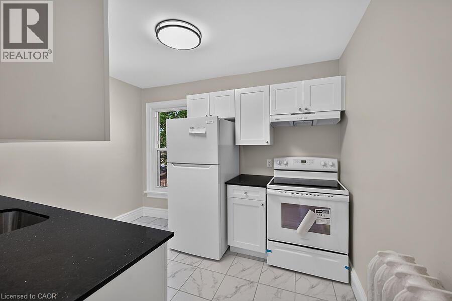 Kitchen featuring white cabinetry, dark speckled countertops, and an electric range with an overhead vent - 103 Mary Street, Hamilton, ON - Indoor Photo Showing Kitchen