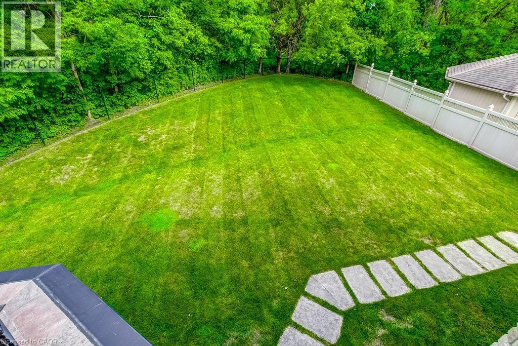 Expansive green lawn surrounded by mature trees, featuring a stone paver pathway and a privacy fence - 172 Diiorio Circle, Ancaster, ON - Outdoor