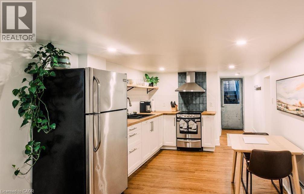 Compact kitchen featuring stainless steel appliances, wood-finish flooring, white cabinetry, wood countertops, and a tiled backsplash - 47 Eagle Avenue, Brantford, ON - Indoor Photo Showing Kitchen