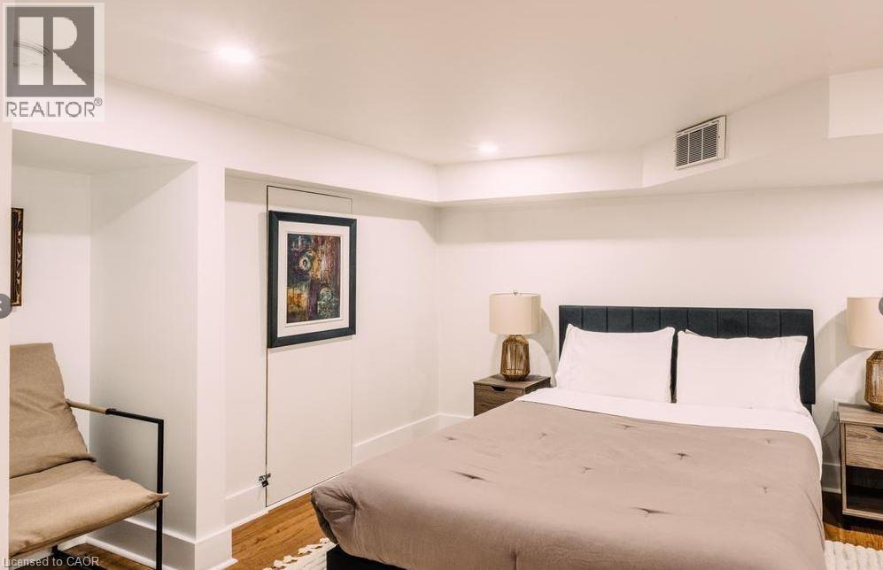 Recessed lighting illuminates this space featuring wood-finish flooring, white walls, and a built-in architectural niche - 47 Eagle Avenue, Brantford, ON - Indoor Photo Showing Bedroom