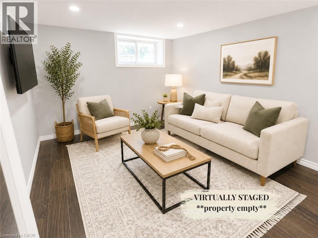 Spacious living area featuring recessed lighting, dark wood-finish flooring, a neutral color palette, and a window providing natural light - 90 Arlington Boulevard Unit# Bsmt, Kitchener, ON - Indoor Photo Showing Living Room