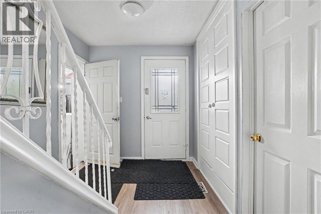 Entryway featuring wood-finish flooring, a white paneled front door with decorative glass inserts, and an iron baluster staircase - 47 Bowman Street, Hamilton, ON - Indoor Photo Showing Other Room