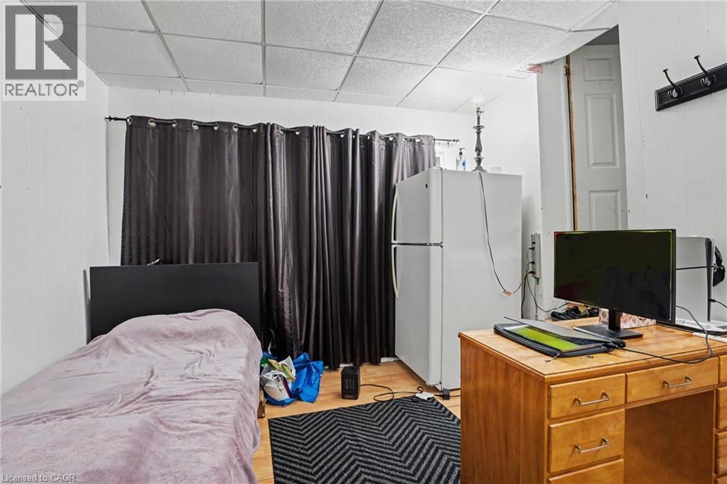 Room featuring paneling on walls, wood-finish flooring, and a grid panel ceiling - 47 Bowman Street, Hamilton, ON - Indoor Photo Showing Bedroom