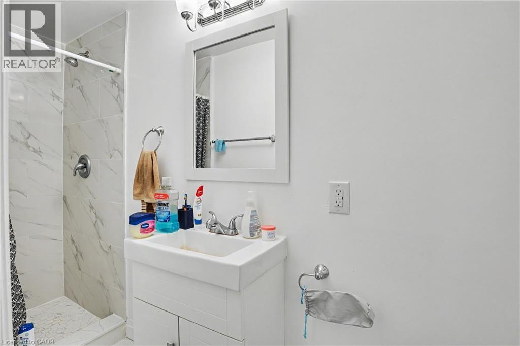 Bathroom featuring a white vanity with integrated sink, chrome faucet, and a wall-mounted mirror with an overhead light fixture - 47 Bowman Street, Hamilton, ON - Indoor Photo Showing Bathroom