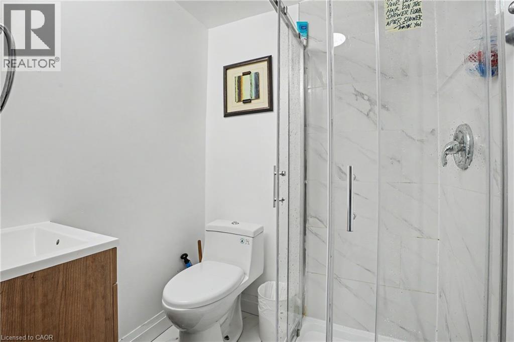 Shower enclosure featuring clear glass panels and white marble-look tile surround - 47 Bowman Street, Hamilton, ON - Indoor Photo Showing Bathroom