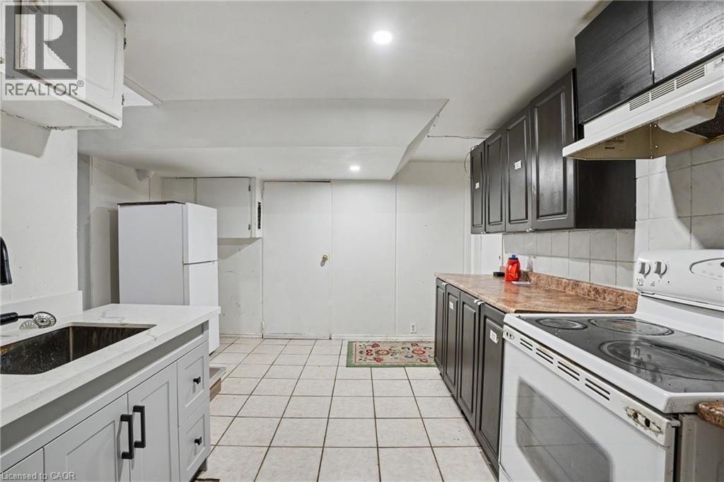 Functional kitchen featuring tile flooring, white appliances, dark cabinetry, and light-colored countertops - 47 Bowman Street, Hamilton, ON - Indoor Photo Showing Kitchen