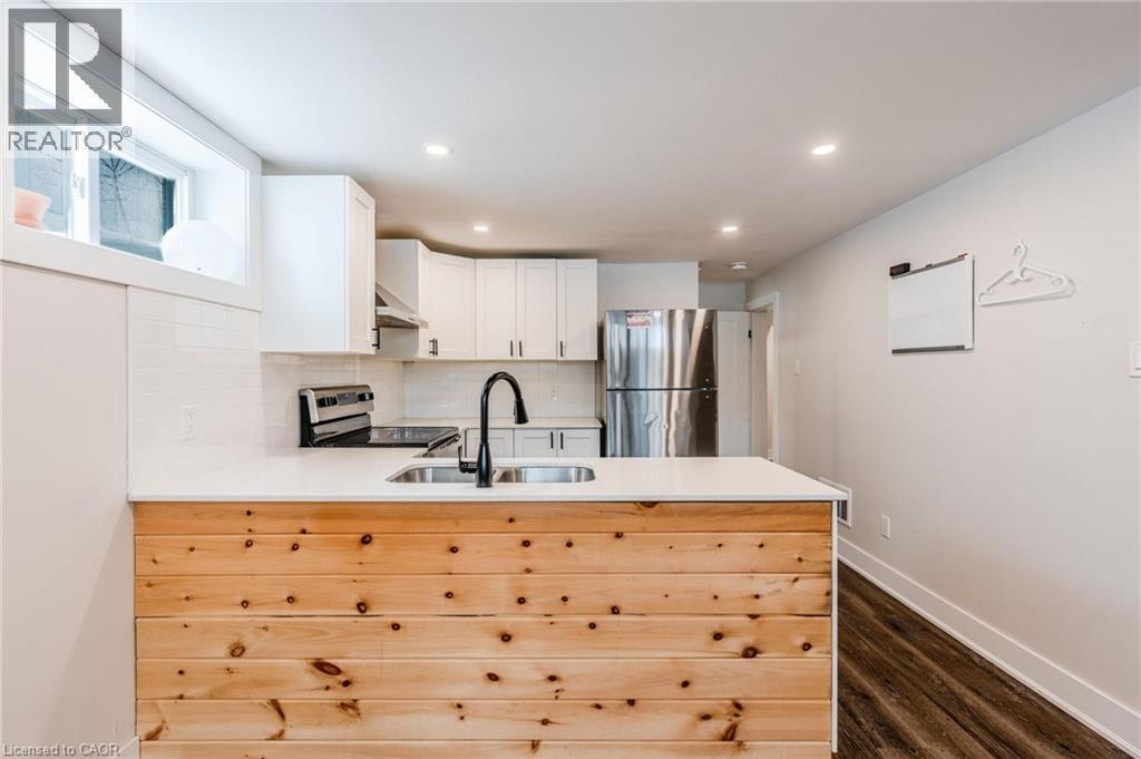 Modern kitchen featuring a wood-panel island with a white countertop and an undermount sink with a matte black faucet - 16 Ronaldshay Avenue, Hamilton, ON - Indoor Photo Showing Kitchen With Double Sink