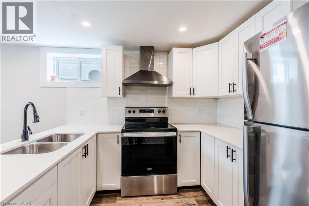 Modern kitchen featuring white shaker-style cabinetry, a white subway tile backsplash, and light-toned countertops - 16 Ronaldshay Avenue, Hamilton, ON - Indoor Photo Showing Kitchen With Double Sink