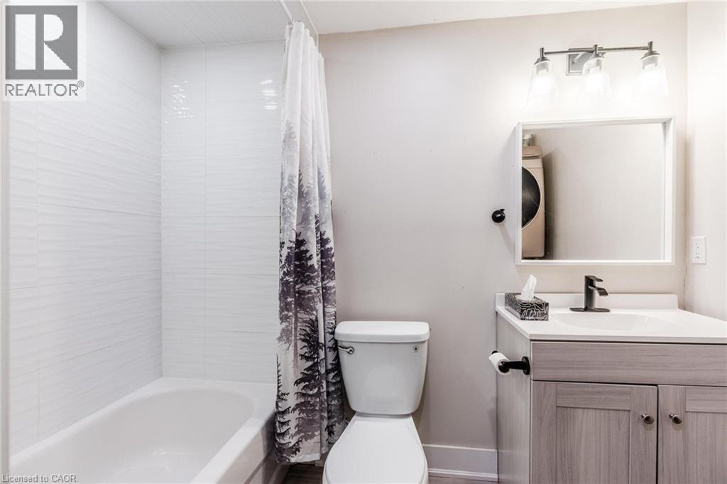 Bathroom featuring a white subway tile shower surround with horizontal texture, a white bathtub, and a vanity with a light wood-finish cabinet - 16 Ronaldshay Avenue, Hamilton, ON - Indoor Photo Showing Bathroom