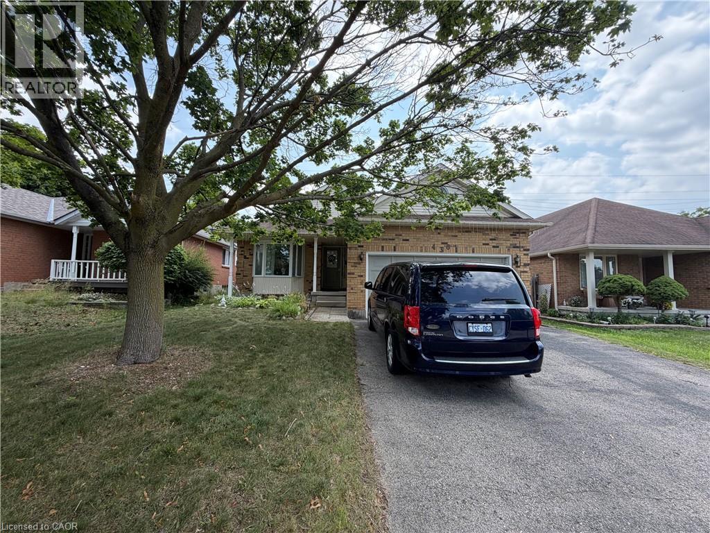 Brick exterior featuring an attached garage, a paved driveway, and a front lawn with mature trees - 436 Gatestone Boulevard, Waterloo, ON - Outdoor