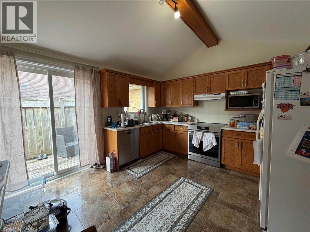 Kitchen featuring wood cabinetry, stainless steel appliances, and a vaulted ceiling with an exposed beam - 436 Gatestone Boulevard, Waterloo, ON - Indoor Photo Showing Kitchen With Double Sink