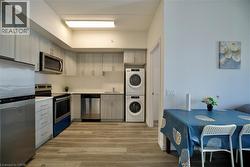 Kitchen featuring wood-finish flooring, light grey cabinetry, stainless steel appliances, and solid surface countertops -