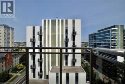Balcony with metal railing and glass panels overlooking an urban landscape with multiple high-rise buildings -
