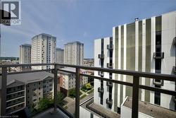 Balcony with glass panel railing and aluminum handrail overlooking urban architecture, featuring multiple high-rise buildings and paved street -