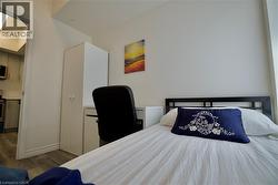 Bedroom featuring plank wood-finish flooring, white walls, and a built-in wardrobe -