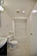 Full bathroom featuring a white drop-in bathtub with shower surround, a white toilet, and a vanity with a white basin -