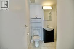 Compact bathroom with light tile flooring and white walls -