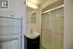 Full bathroom featuring a shower with sliding glass doors, a vanity with an integrated sink and dark cabinetry, a wall-mounted mirror, and an overhead light fixture -
