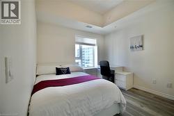 Bedroom featuring a large window, light wood-finish flooring, white baseboards, and a high ceiling -