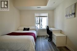 Bright bedroom featuring a large window with roller shade, wood-finish flooring, recessed lighting, and a built-in desk with integrated storage -