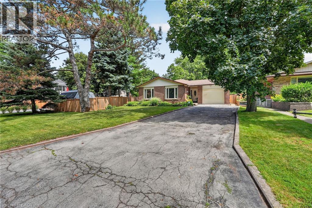 Brick exterior home featuring a front-facing garage, manicured front lawn, and mature trees - 3 Orchard Parkway, Grimsby, ON - Outdoor