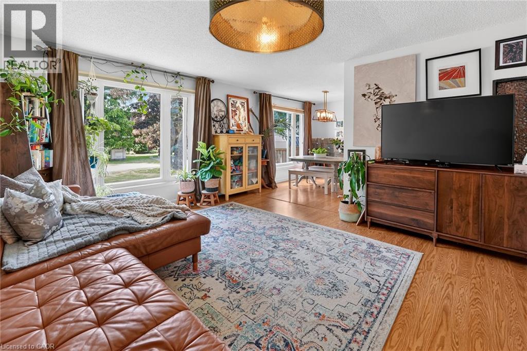 Open-concept living area featuring wood-finish flooring, a contemporary ceiling fixture, large picture windows, and a dedicated dining space - 3 Orchard Parkway, Grimsby, ON - Indoor Photo Showing Living Room