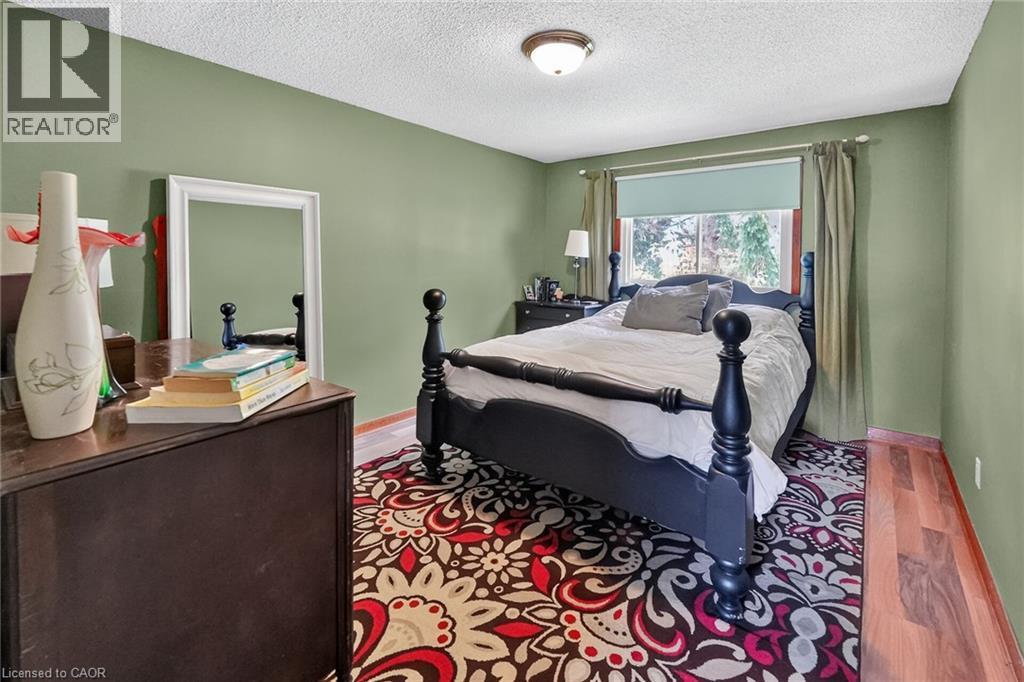 Room featuring light green walls, wood-finish flooring, a ceiling-mounted light fixture, and a window with a roller shade - 3 Orchard Parkway, Grimsby, ON - Indoor Photo Showing Bedroom