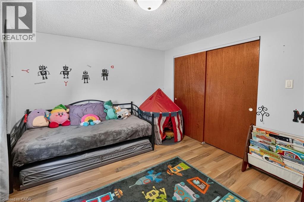 Room featuring wood-finish flooring, two large sliding closet doors, and overhead lighting - 3 Orchard Parkway, Grimsby, ON - Indoor Photo Showing Bedroom