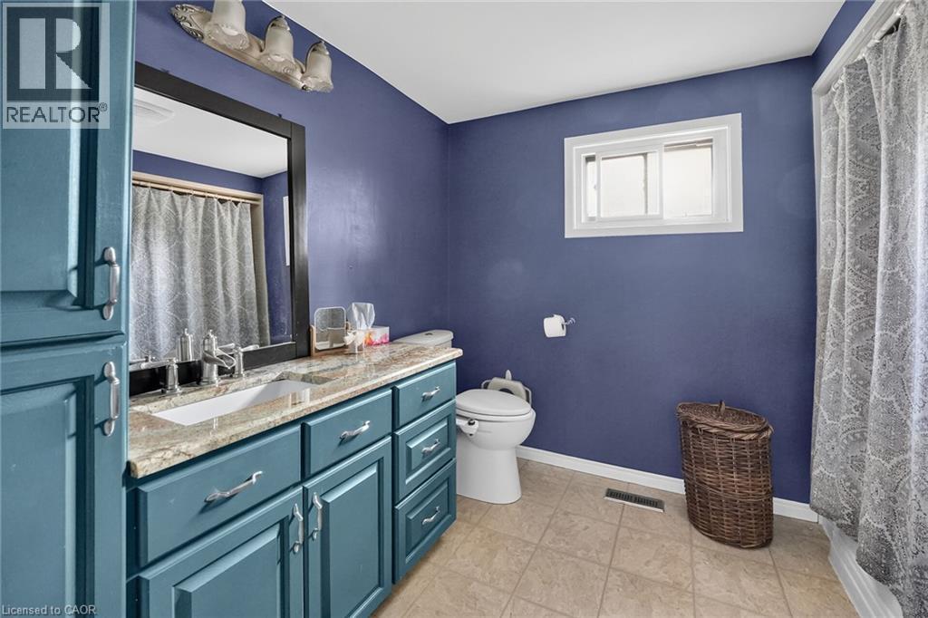 Bathroom featuring a vanity with a light-colored countertop, an undermount sink, and blue cabinetry - 3 Orchard Parkway, Grimsby, ON - Indoor Photo Showing Bathroom