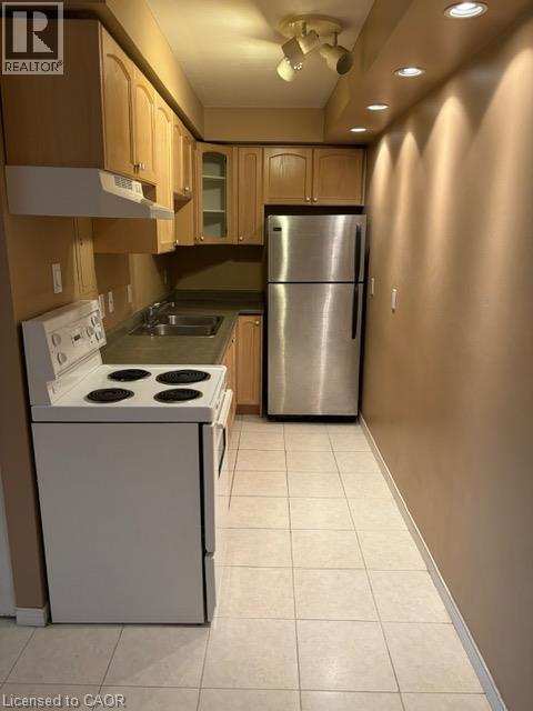 Compact kitchen featuring light wood cabinetry, a stainless steel refrigerator, and a white electric range - 30 Summit Avenue Unit# 604, Hamilton, ON - Indoor Photo Showing Kitchen