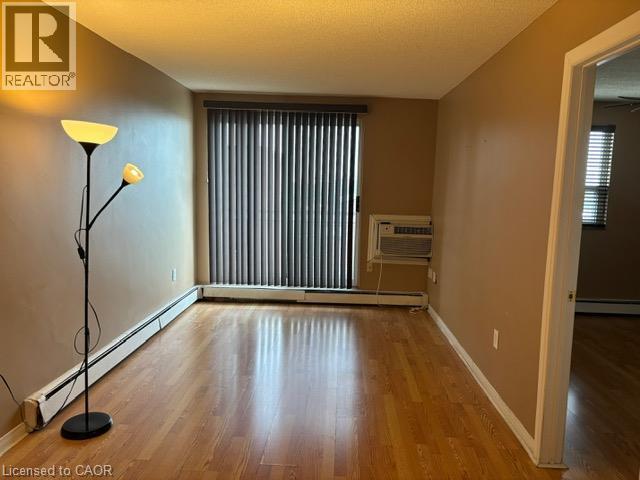 Warm-toned walls and wood-finish flooring define this interior space - 30 Summit Avenue Unit# 604, Hamilton, ON - Indoor Photo Showing Other Room