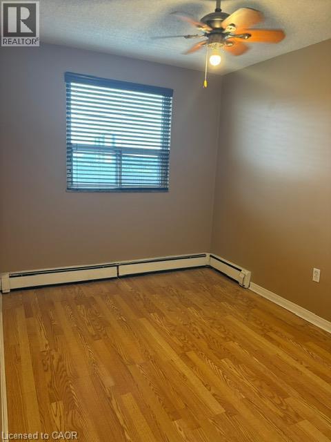 Room featuring wood-finish flooring, a ceiling fan with integrated lighting, and baseboard heating - 30 Summit Avenue Unit# 604, Hamilton, ON - Indoor Photo Showing Other Room