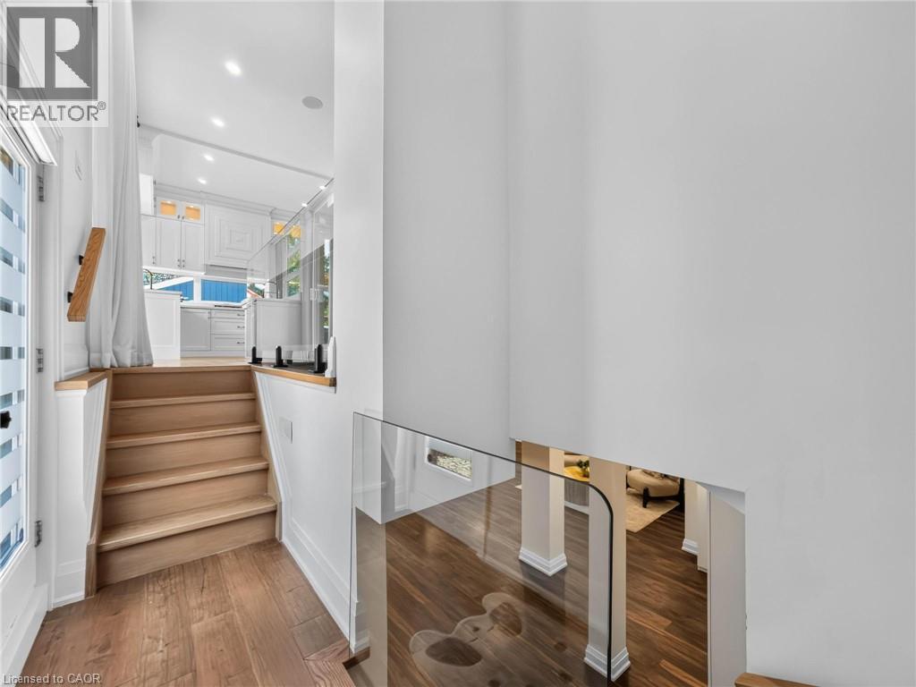 Multi-level interior featuring wood-finish flooring, glass panel railings, and recessed lighting - 5178 Hunter Drive, Burlington, ON - Indoor Photo Showing Other Room