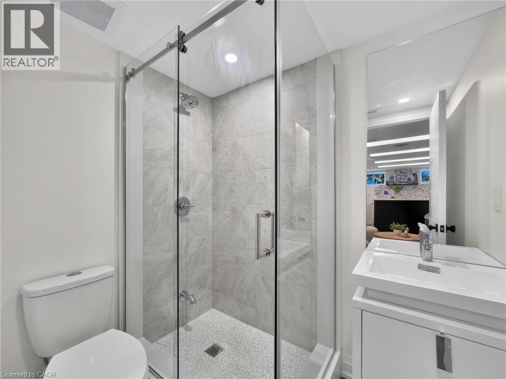 Bathroom featuring a frameless glass shower enclosure, white pebble shower floor, large format tile shower walls, and a contemporary vanity with an integrated sink - 5178 Hunter Drive, Burlington, ON - Indoor Photo Showing Bathroom