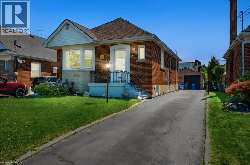 Brick bungalow with a prominent front yard, an extended driveway, and a detached garage structure - 127 Taylor Avenue, Hamilton, ON - Outdoor