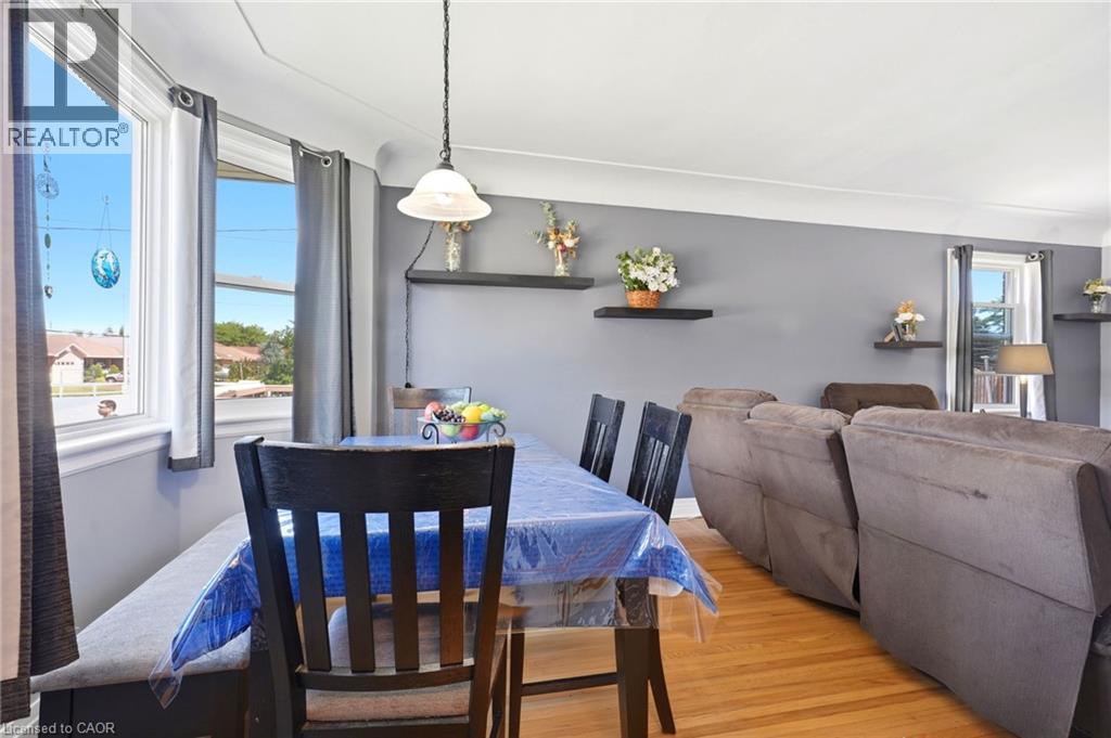 Dining area featuring wood-finish flooring, a pendant light fixture, and large windows - 127 Taylor Avenue, Hamilton, ON - Indoor Photo Showing Dining Room