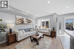 Spacious living area featuring recessed lighting, light wood-finish flooring, and a large window with white blinds - 